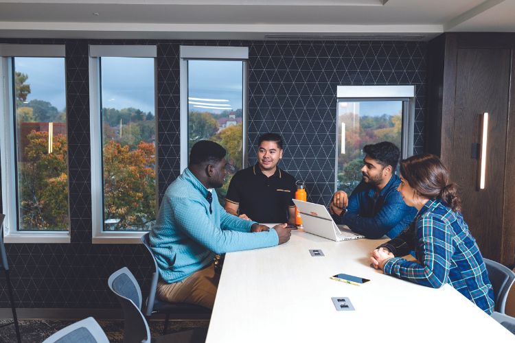 Students sit around large tables in a new, upgraded space in Bloch Heritage Hall